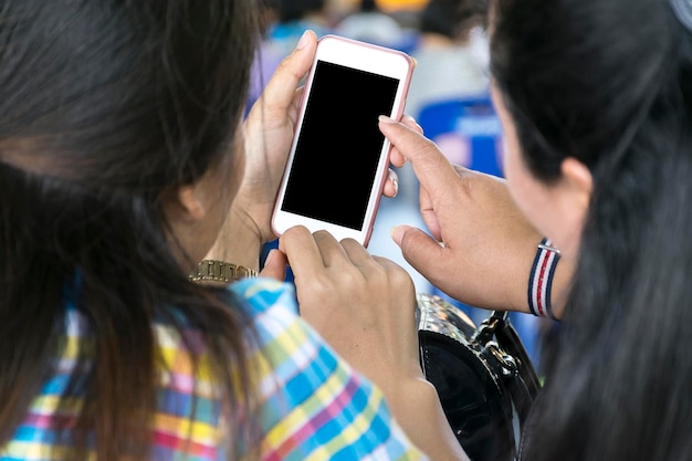 2 girlsHand holding mobile with grocery online on screen with blur supermarket backgroundSmart phone online shopping in woman hand and retail concept