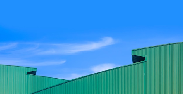 写真 2 緑色の波紋金属の曲がりくねった屋根 現代の産業用倉庫の建物と青い空