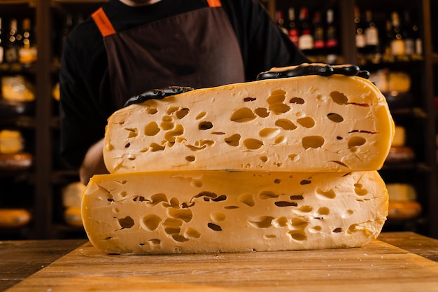 2 metà di formaggio giallo forma limitata maasdam naturale stagionato taglio del formaggio in negozio grandi pezzi di formaggio sommelier che tiene il formaggio