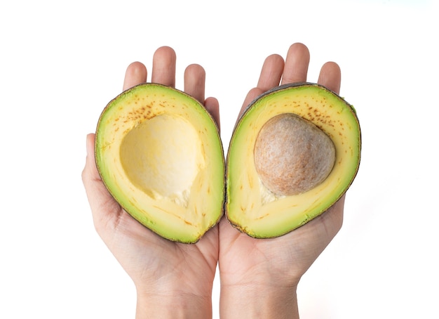 2 hand holding avocado cut in half isolated on a white background, the flesh of the avocado is creamy and soft with a buttery taste. Avocados contain nutrients, vitamins and good fats.