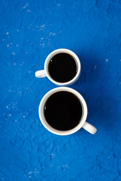 2 kopjes koffie op een blauwe ondergrond.