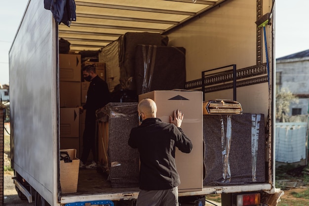 2 men placing bundles inside a moving truck
