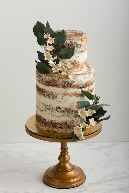 Photo 2 tier unfrosted wedding cake on marble table with gray background