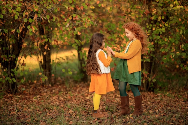 2 vrolijke brunette en roodharige meisjes voor een wandeling in het herfstpark.