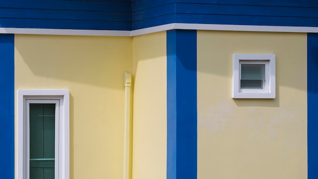 2 white fixing windows with air vent pipe on yellow and blue house building wall in modern style