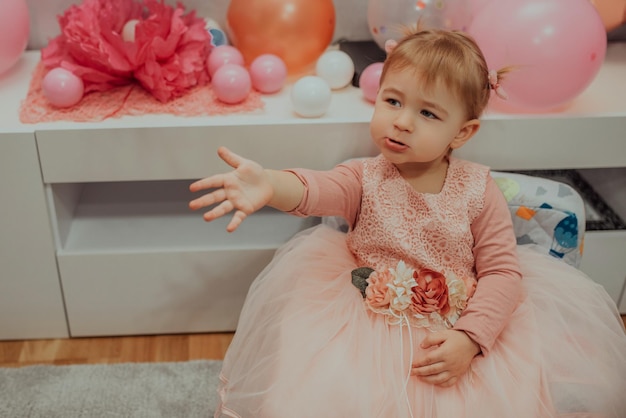 2 year baby girl in pink dress with her first birthday cake\
happy birthday carda cute little girl celebrates her first birthday\
surrounded by gifts