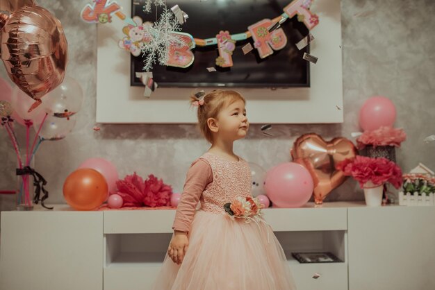 2 year baby girl in pink dress with her first birthday cake\
happy birthday carda cute little girl celebrates her first birthday\
surrounded by gifts