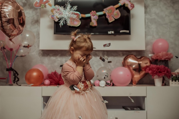 2 year baby girl in pink dress with her first birthday cake\
happy birthday carda cute little girl celebrates her first birthday\
surrounded by gifts