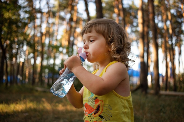 2 years kid drinking water from plastic bottle Child girl was thirsty