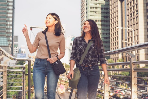 2 young women walking with urban city buildings in background