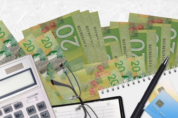 20 캐나다 달러 지폐와 계산기 안경 및 펜. 납세 시즌 개념 또는 투자 솔루션. 재무 계획 또는 회계사 서류