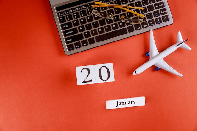 コンピューターのキーボード、飛行機、メガネ赤背景にビジネスワークスペースオフィスデスク上のアクセサリーと1月20日カレンダー