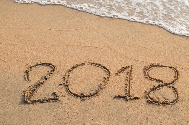 Foto 2018 bericht geschreven in het zand op de achtergrond van het strand