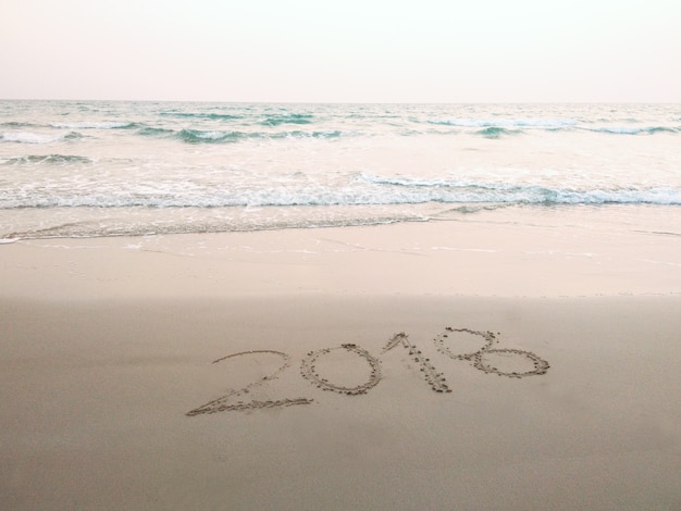 2018 scritto sulla spiaggia di sabbia con la riva del mare