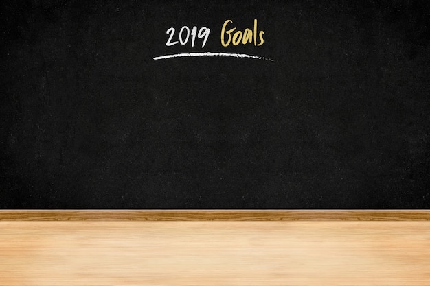 Scrittura di 2019 obiettivi sulla parete della lavagna sul pavimento di legno della plancia, presentati di affari del nuovo anno