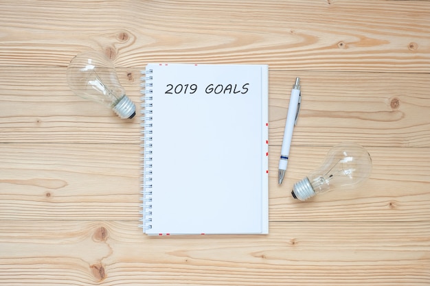 2019 Goals with lightbulb  and crumbled paper  on table.
