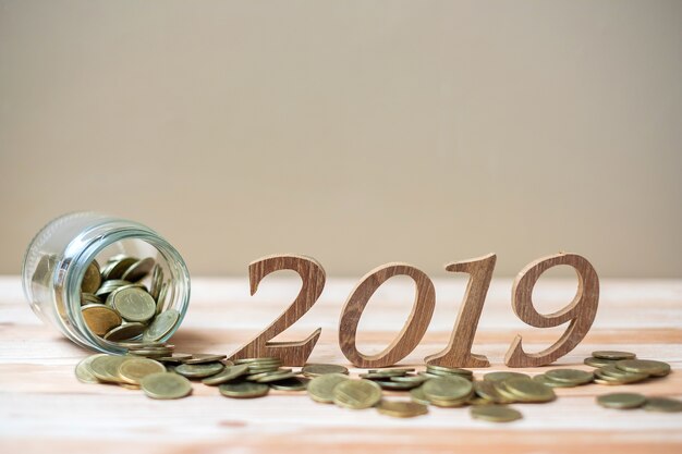 2019 Happy New Year with gold coins stack and wooden number on table