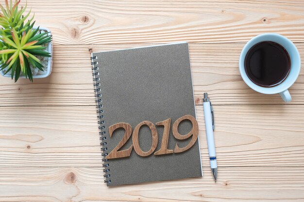 2019 Happy New Year with notebook, black coffee cup, pen and glasses 