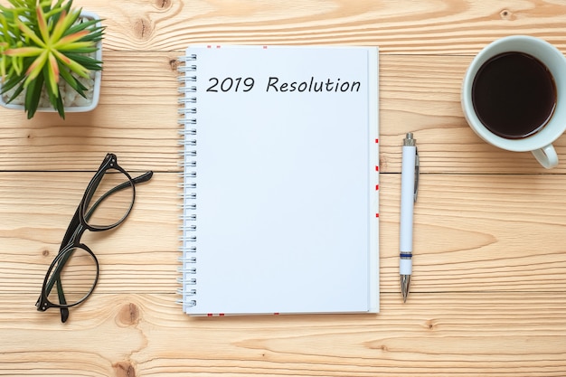 2019 Resolutions with notebook, black coffee cup, pen and glasses 