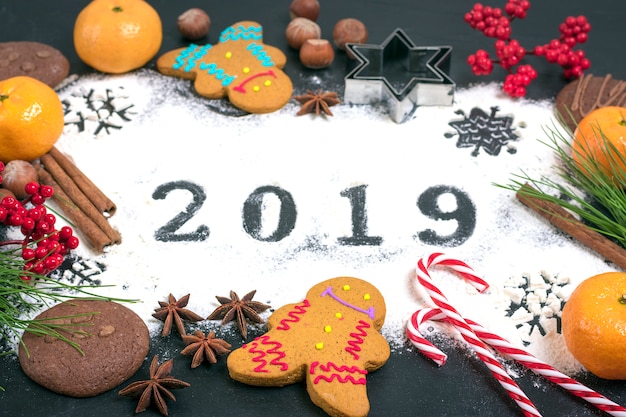 2019 text made with flour with decorations on black background.