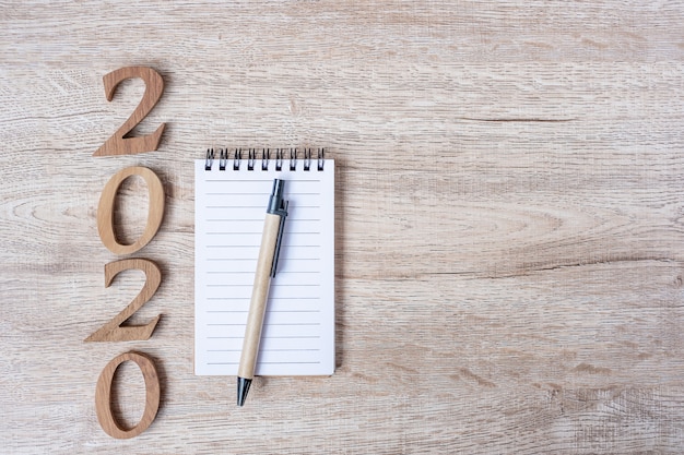 2020 Happy New years with paper notebook, pen and wooden number 