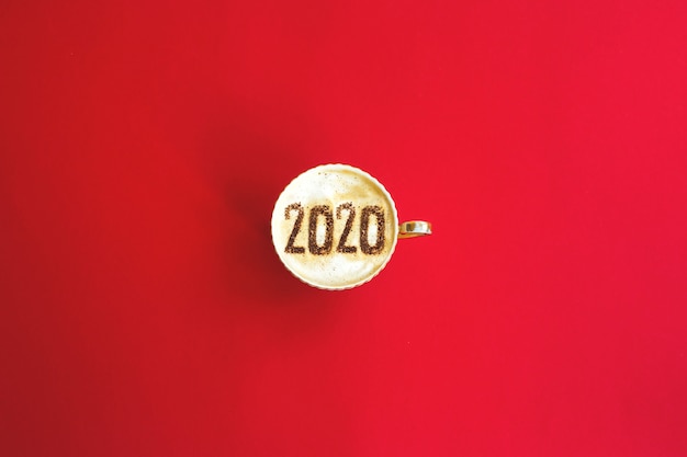 2020 jaar concept inscriptie op een kopje cappuccino op rood.