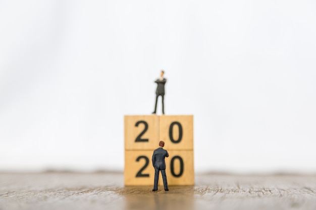 2020 nieuwjaar en bedrijfsplanning. Sluit omhoog van twee zakenman miniatuurcijfer zich bevindt voor stapel houten aantalblokken