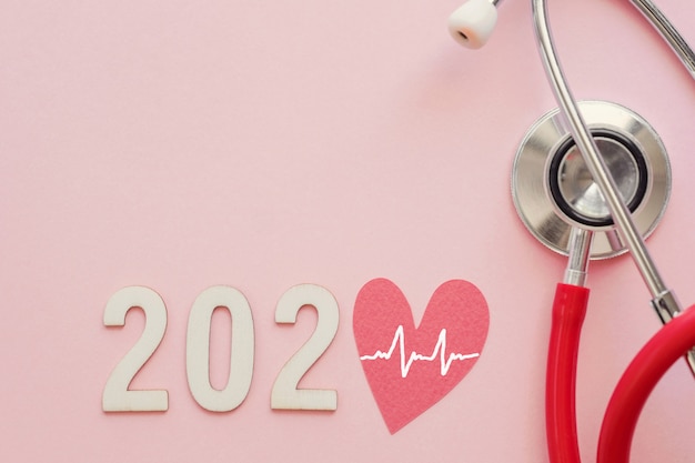 2020 wooden number with red heart and stethoscope on pink background