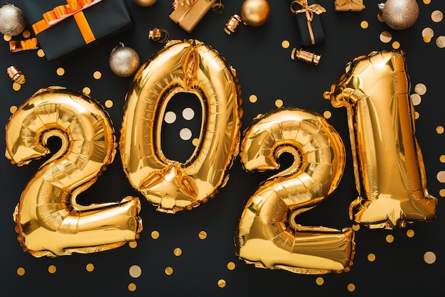 Palloncino oro 2021 con coriandoli, scatole regalo, palline d'oro, decorazioni festive buon anno 2021.