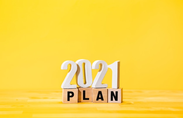 Бизнес-план на 2021 год с текстом на деревянной коробке на желтом фоне. видение успеха