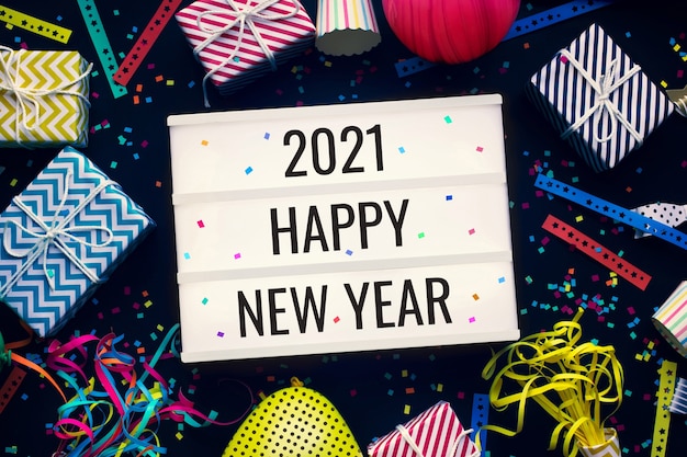 2021 happy new year and celebration concepts with text on cinema light box and colorful party prop on dark background.funny and festival activity