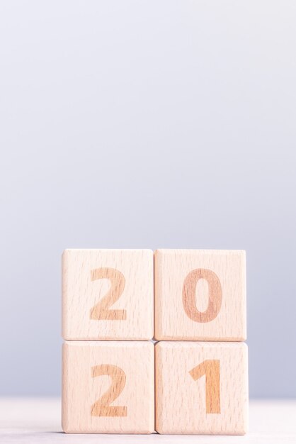 写真 2021年新年の抽象的なデザインコンセプト-木製のテーブルと水色の背景に分離された数の木製ブロックキューブ。