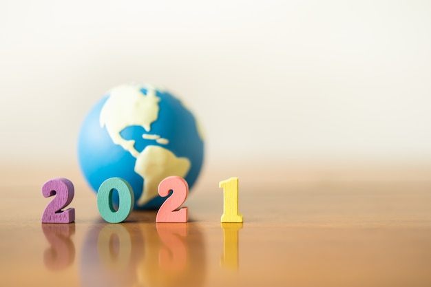 2021 New year , Global and Business concept. Close up of colorful wooden number with mini world toy ball on wooden table and copy space