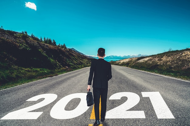 Photo the 2021 new year journey and future vision concept . businessman traveling on highway road leading forward to happy new year celebration in beginning of 2021 for fresh and successful start .