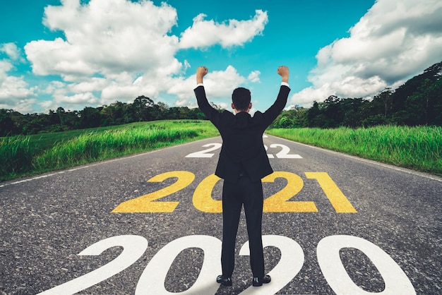 The 2021 New Year journey and future vision concept . Businessman traveling on highway road leading forward to happy new year celebration in beginning of 2021 for fresh and successful start .