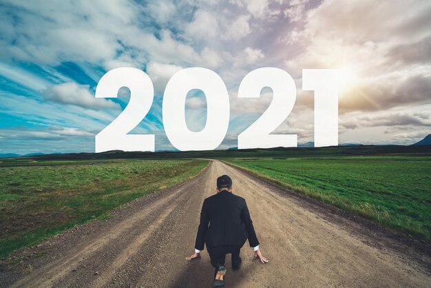 2021年の新年の旅と将来のビジョンのコンセプト。新鮮で成功したスタートのために2021年の初めに新年あけましておめでとうございますのお祝いにつながる高速道路を旅するビジネスマン。