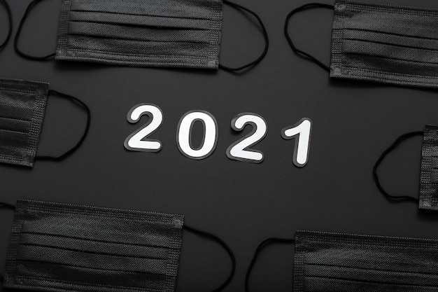 Photo 2021 text lettering in black medical face mask pattern frame. new year 2021 in covid lockdown.