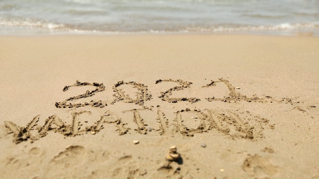 2021 휴가 바다 해변의 모래에 손으로 쓴 비문. 여름
