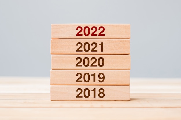 テーブルの背景に2021、2020、2019の木造建築物の2022ブロック。事業計画、リスク管理、解決、戦略、ソリューション、目標、新年とハッピーホリデーの概念