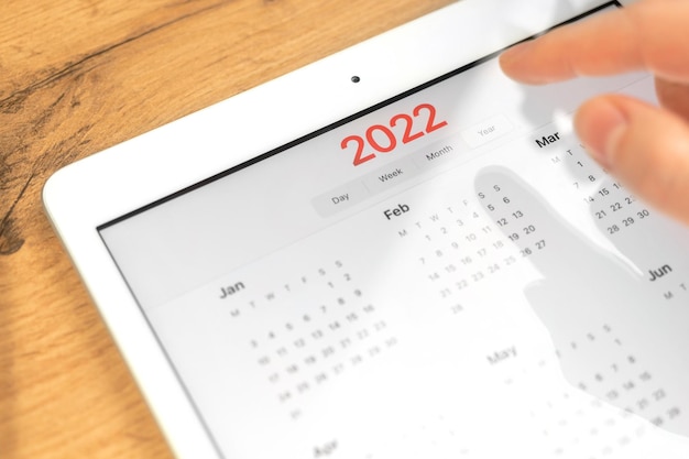 2022년 달력 클로즈업, 태블릿 컴퓨터 화면. 비즈니스 나무 테이블 바탕 화면 배경입니다. 약속 및 회의 계획의 컨셉 사진