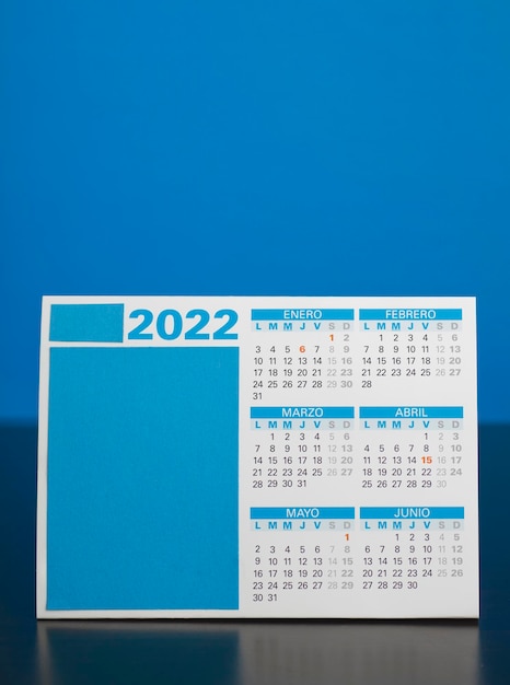 파란색 배경이 있는 나무 책상 테이블에 스페인어로 된 2022년 달력
