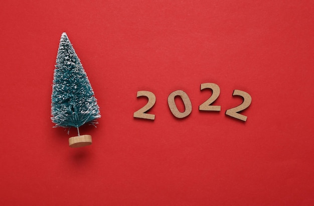 2022 en mini kerstboom op rode achtergrond Kerstmis nieuwjaar samenstelling