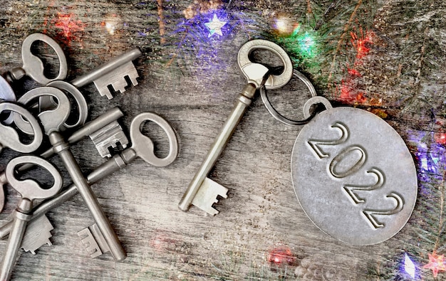 クリスマスライト飾りの背景に古い鍵のリングに刻まれた2022年