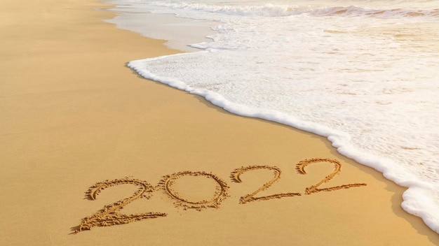 2022 gelukkig nieuwjaar komend concept handgeschreven op het strand