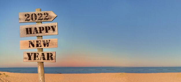 2022 gelukkig nieuwjaar schrijven op een houten bord op het strand in panoramisch uitzicht