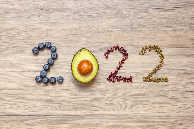 2022년 새해 복 많이 받으시고 과일과 채소로 새해 복 많이 받으십시오. 테이블에 블루베리, 아보카도, 콩. 목표, 건강, 동기 부여, 해결, 새로운 시작 시간, 다이어트 및 세계 식품의 날 개념
