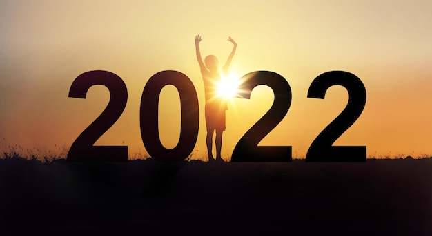 Photo 2022 happy new years christmas eve silhouette a boy is standing arms raised up with happiness