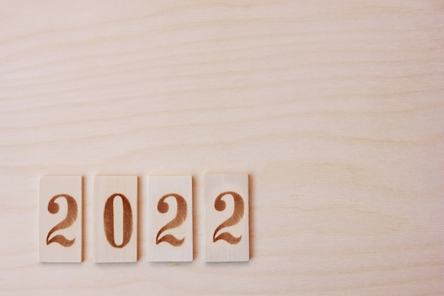 2022 New year number lined with wooden figures on the wooden surface. Happy New Year.