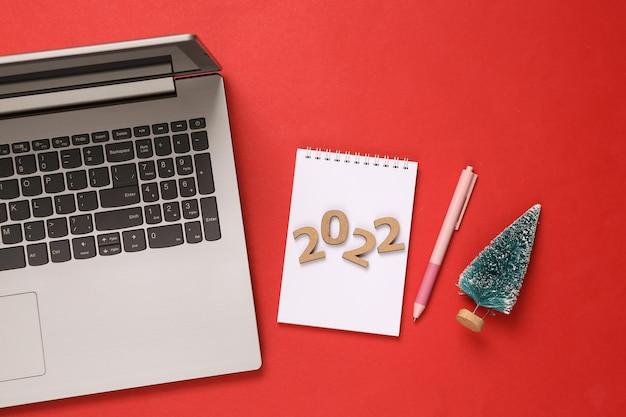 2022 plan laptop Notebook with pen christmas trees on red background