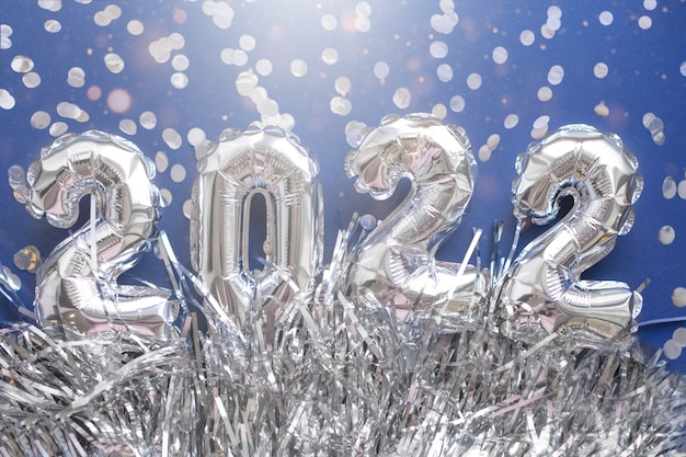 2022 silver numbers inflatable figures on a blue background with confetti. The concept of New Year and Christmas